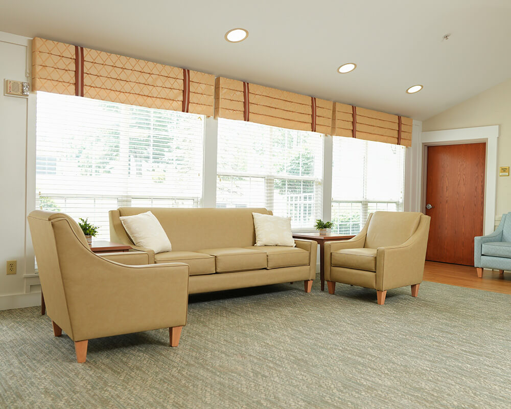 Inviting lounge area with beige furniture and large windows in a residential community.