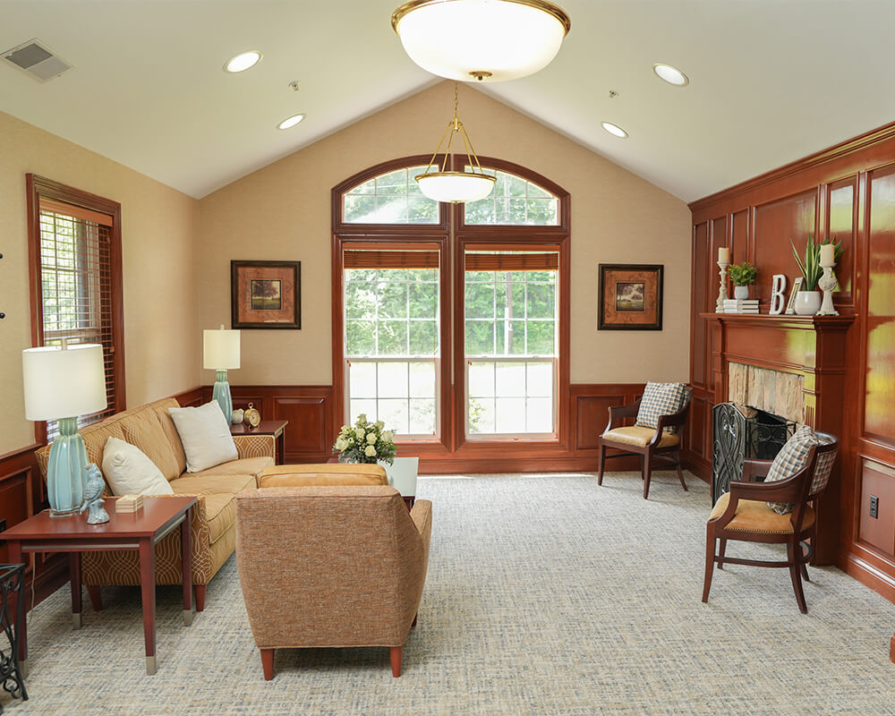 Cozy seating area with sofas, chairs, and a fireplace in a senior living community.