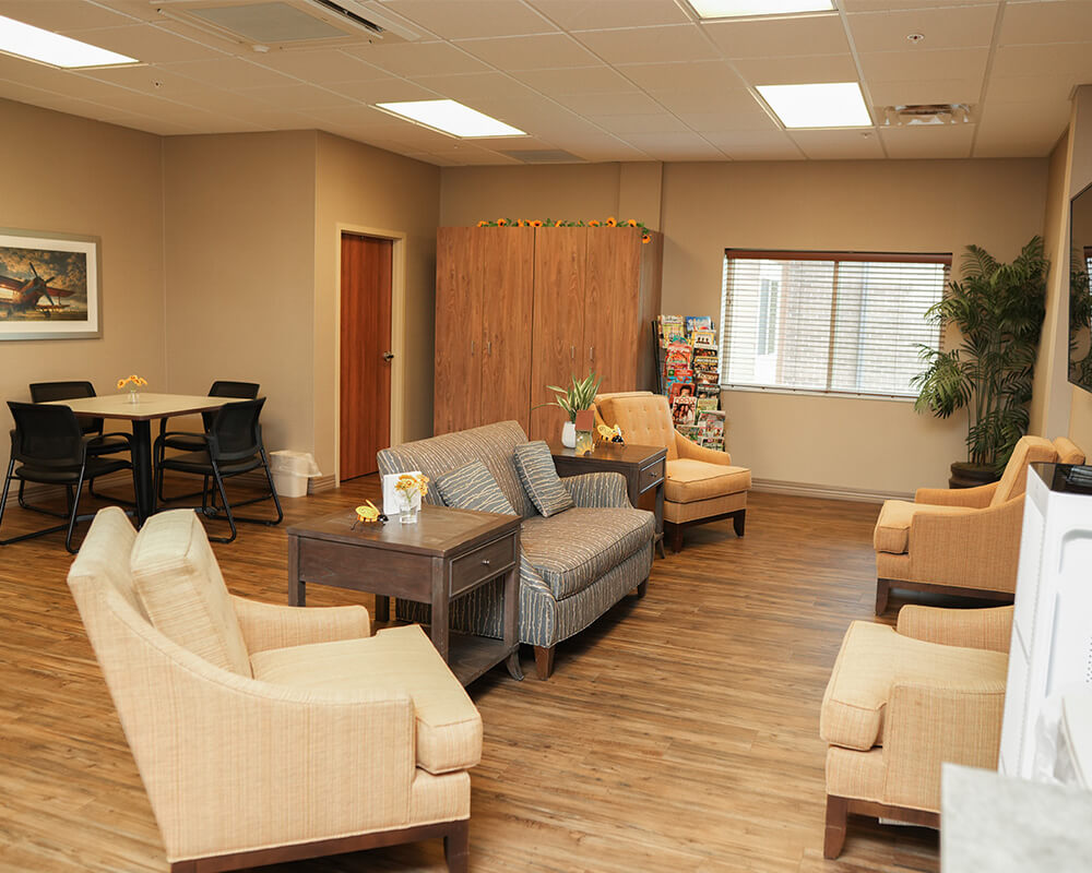 Community lounge with comfortable seating and natural light in senior living facility.