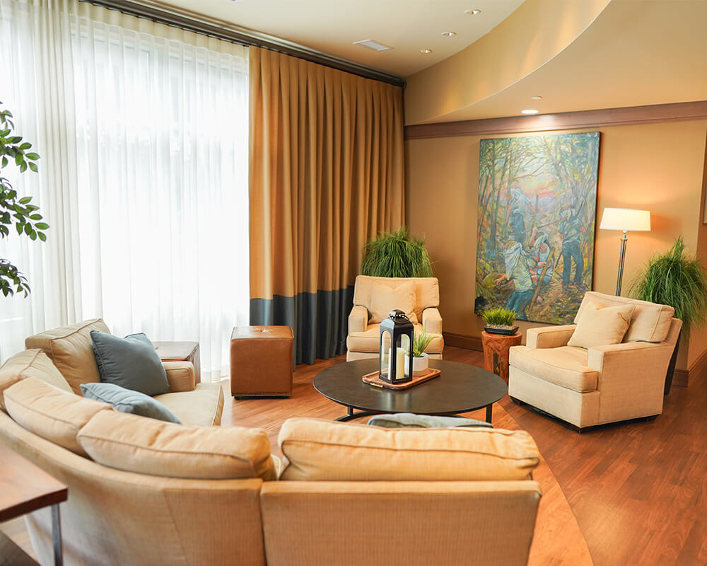 Cozy seating area in a senior living community with beige chairs and artwork.