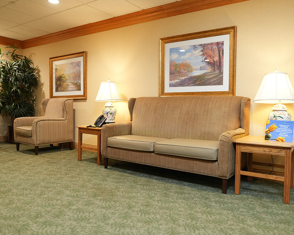 Cozy seating area in a senior living community with beige chairs and artwork.