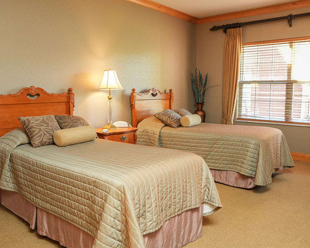 Cozy bedroom with two twin beds, a lamp, and a window with curtains.