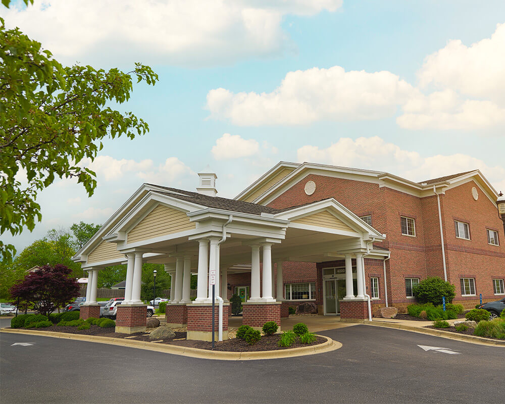 Entrance of a brick senior living community building with white columns.