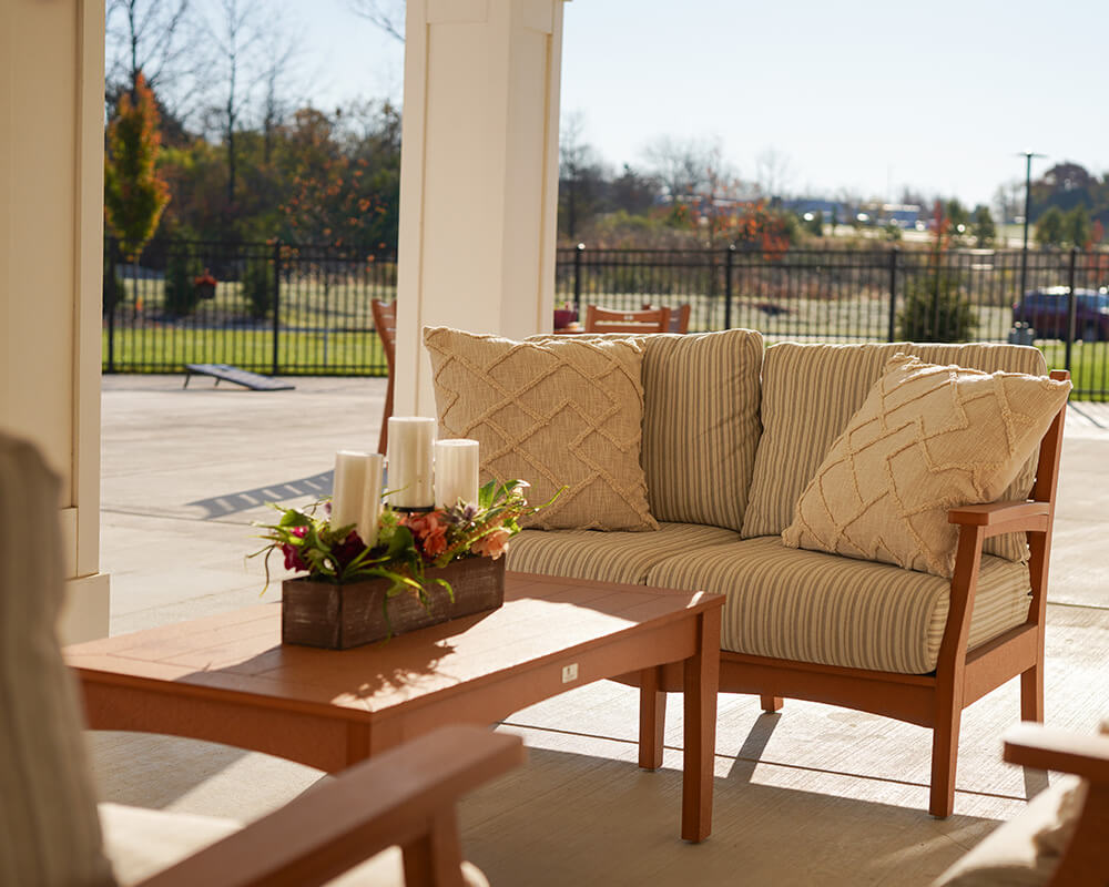 Outdoor seating area with a wooden sofa and decorative candles on a table.