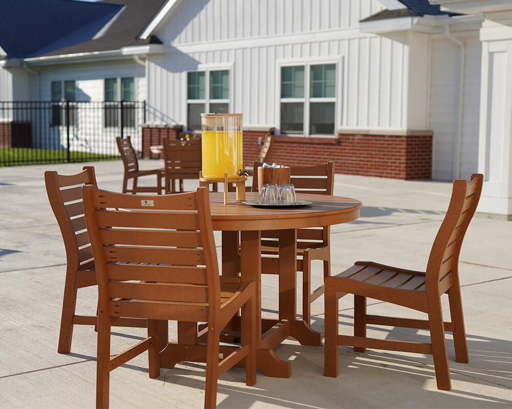 Outdoor patio with wooden table and chairs near a community building.