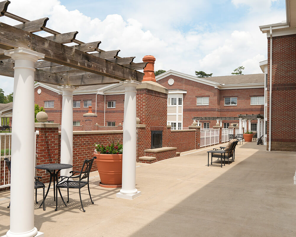 Spacious outdoor patio with seating and wooden pergolas at a brick residential building.