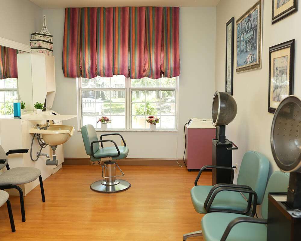 Salon space with styling chairs and hair dryers in a senior living community.