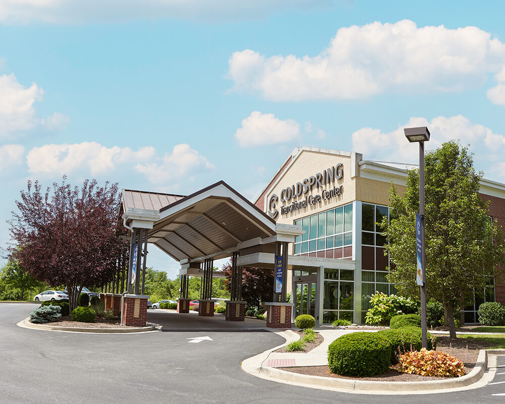 Entrance of a senior community building with landscaped surroundings.