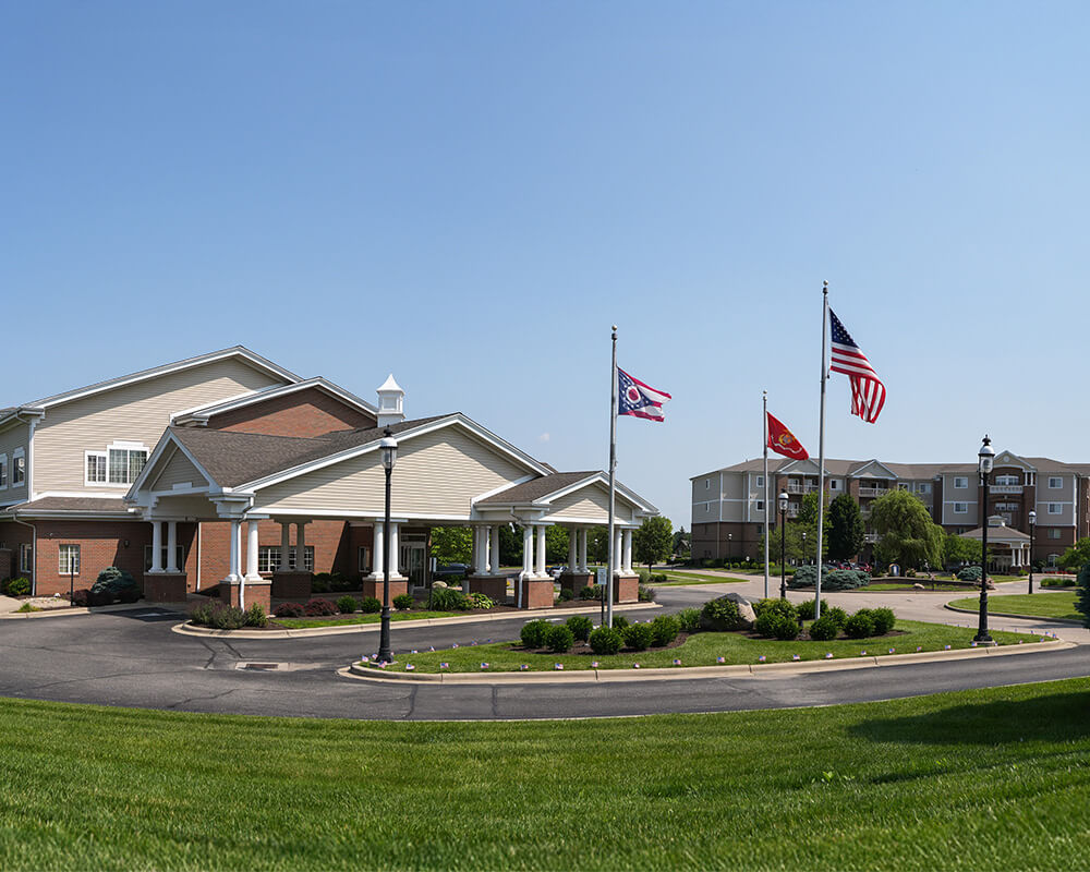 Entrance of a senior community building with landscaped surroundings.