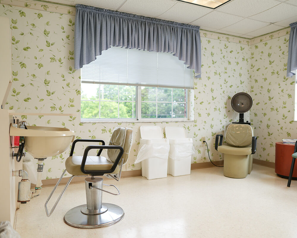 Bright salon area with chair, sink, and dryer in senior living community.