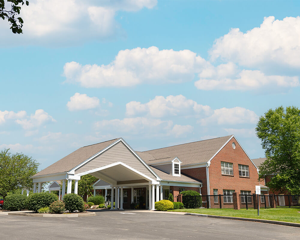 Entrance of a senior living community with brick building under a blue sky.