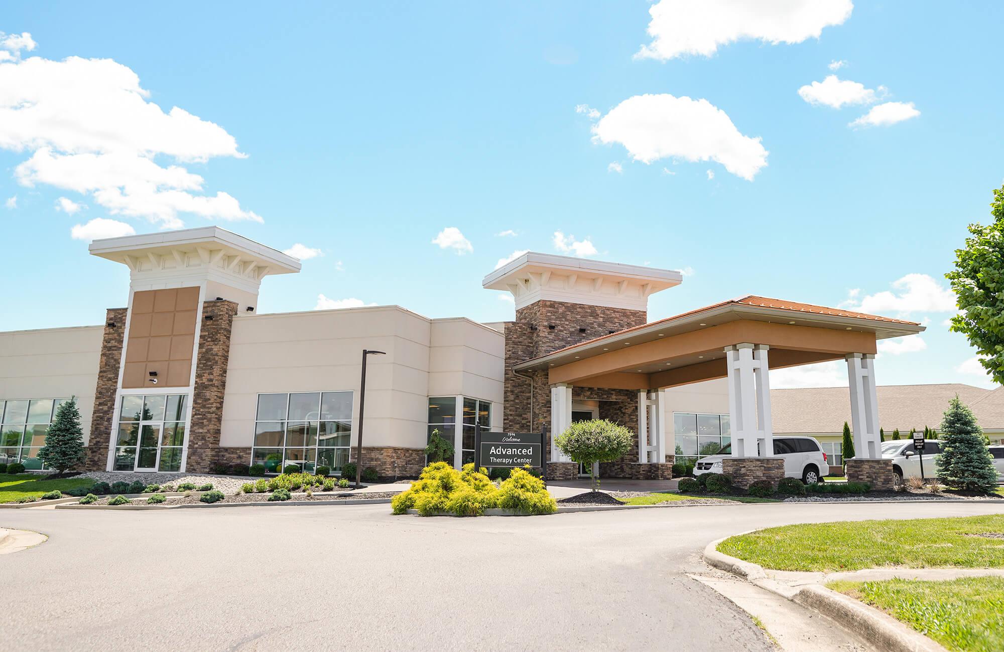 Modern senior living community entrance with a landscaped driveway.