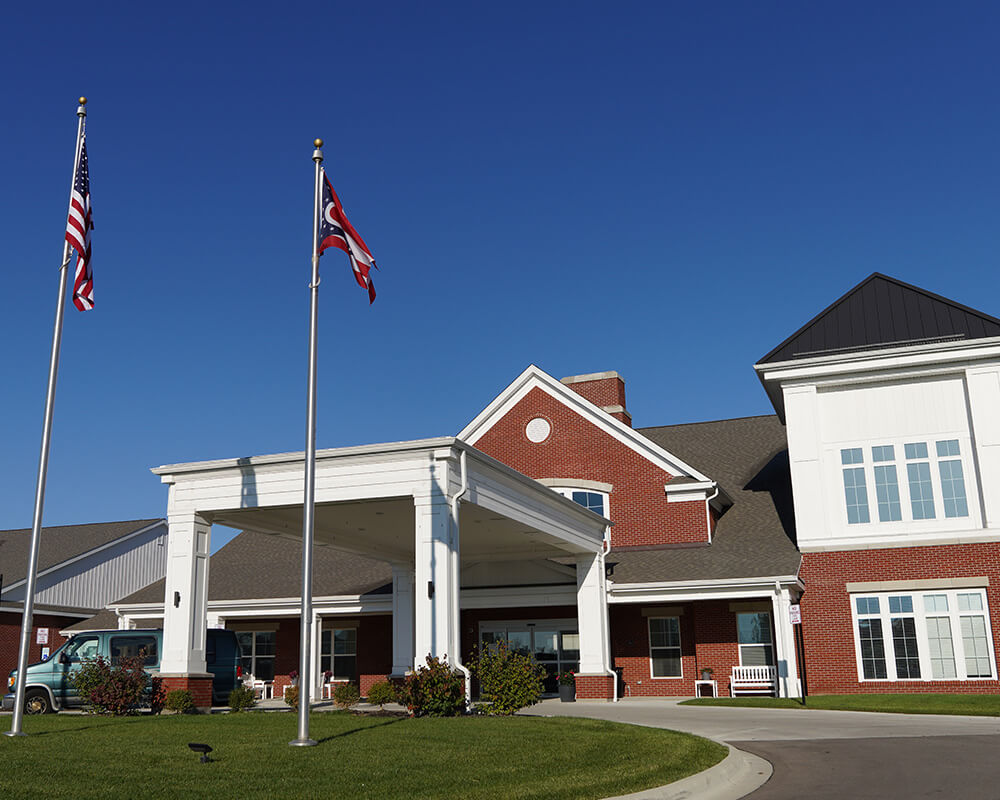 Main entrance of a senior living community with two flags in front.
