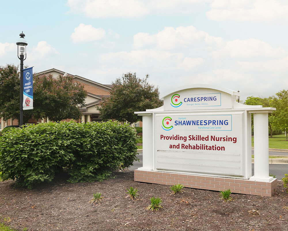 Entrance sign for ShawneeSpring Transitional Care Center with surrounding greenery.