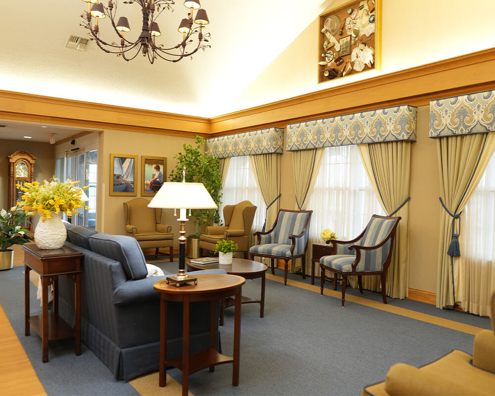 Elegant lounge area with sofas, chairs, chandeliers, and large windows.
