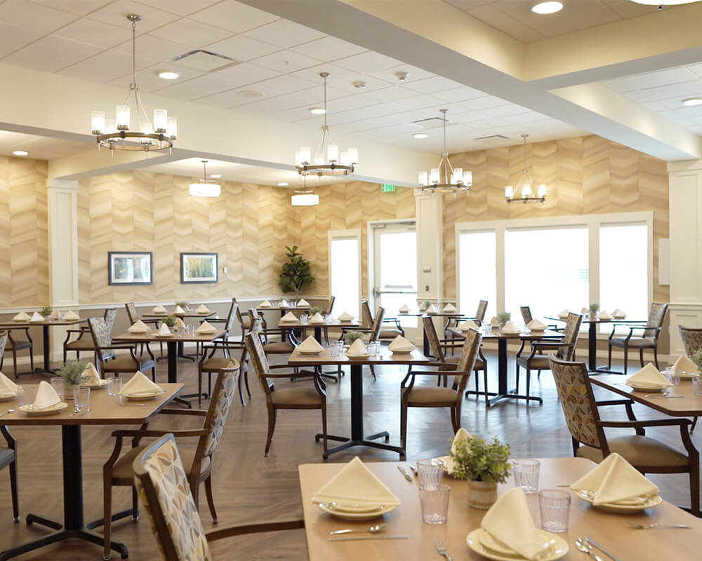 Elegant dining area with tables set for a meal in a senior community.