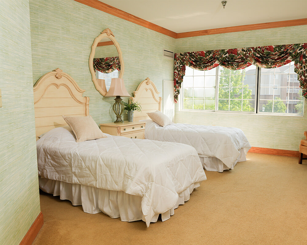 Bright room with two twin beds, floral curtains, and a large window.
