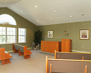 Chapel room with wooden pews and podium in a senior living community.