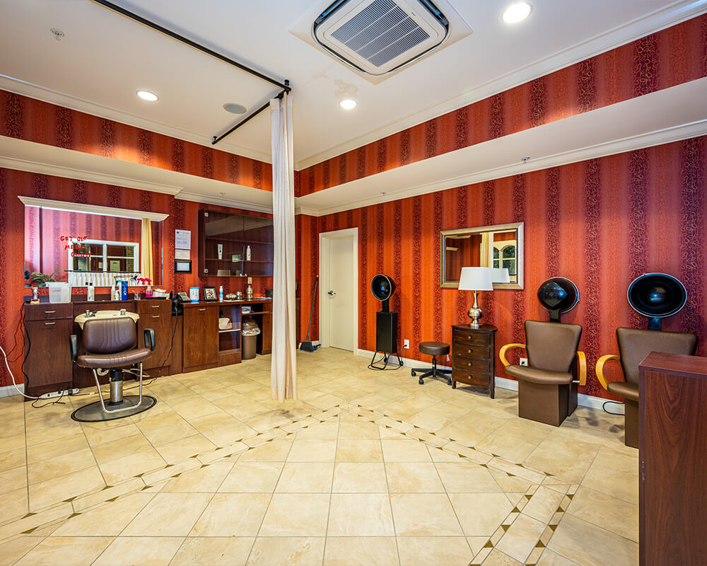 Salon in senior living community with chairs and hairdryers under warm lighting.