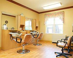 Bright salon in senior community with styling chairs and large mirrors.