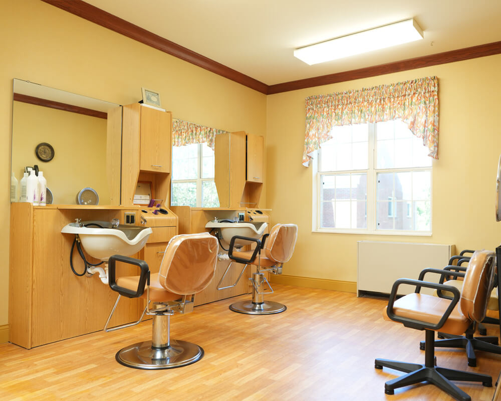 Bright salon in senior community with styling chairs and large mirrors.