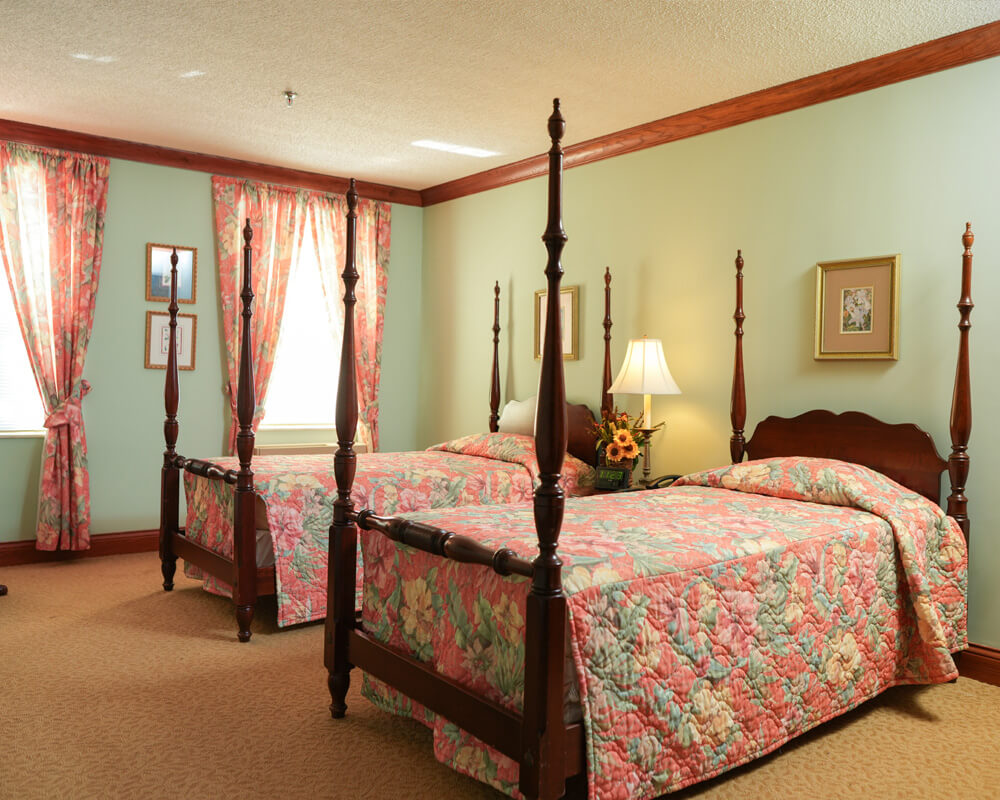 Cozy bedroom with two four-poster beds, floral quilts, and floral curtains.