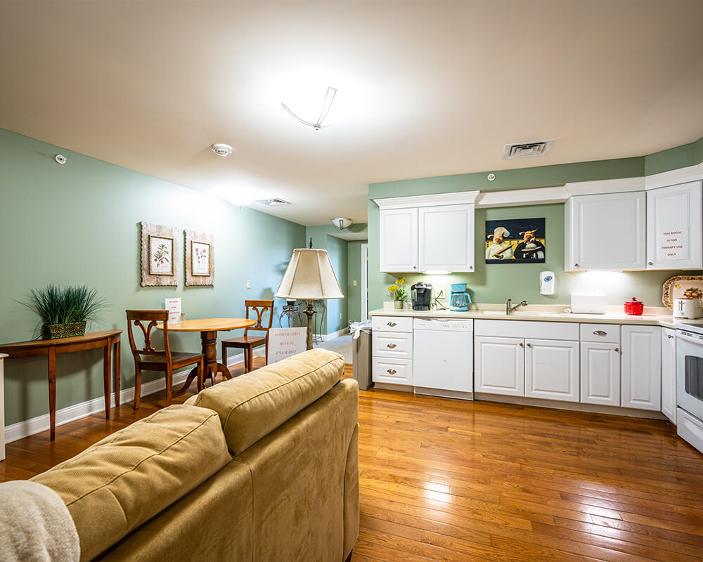 Cozy kitchen and dining area with green walls and wooden flooring in a residential unit.
