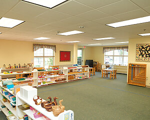 Large bright room with shelves, tables, and educational supplies.