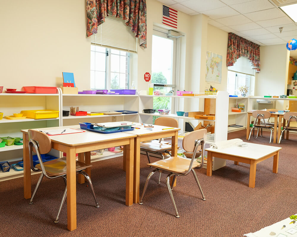 Classroom with tables, chairs, colorful shelves, and an American flag.