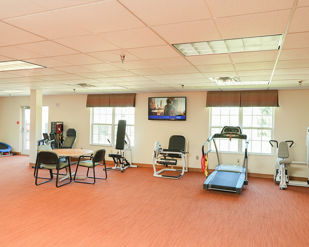Spacious gym area with exercise equipment and seating in a community building.