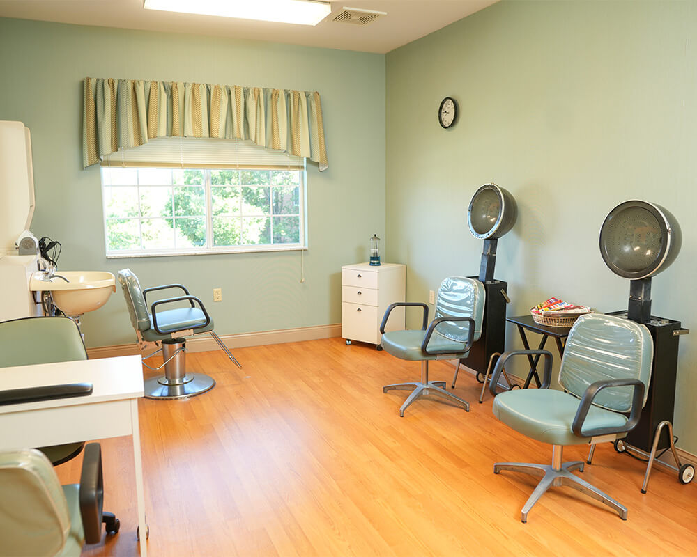 Bright hair salon with chairs and dryers in a senior living community.