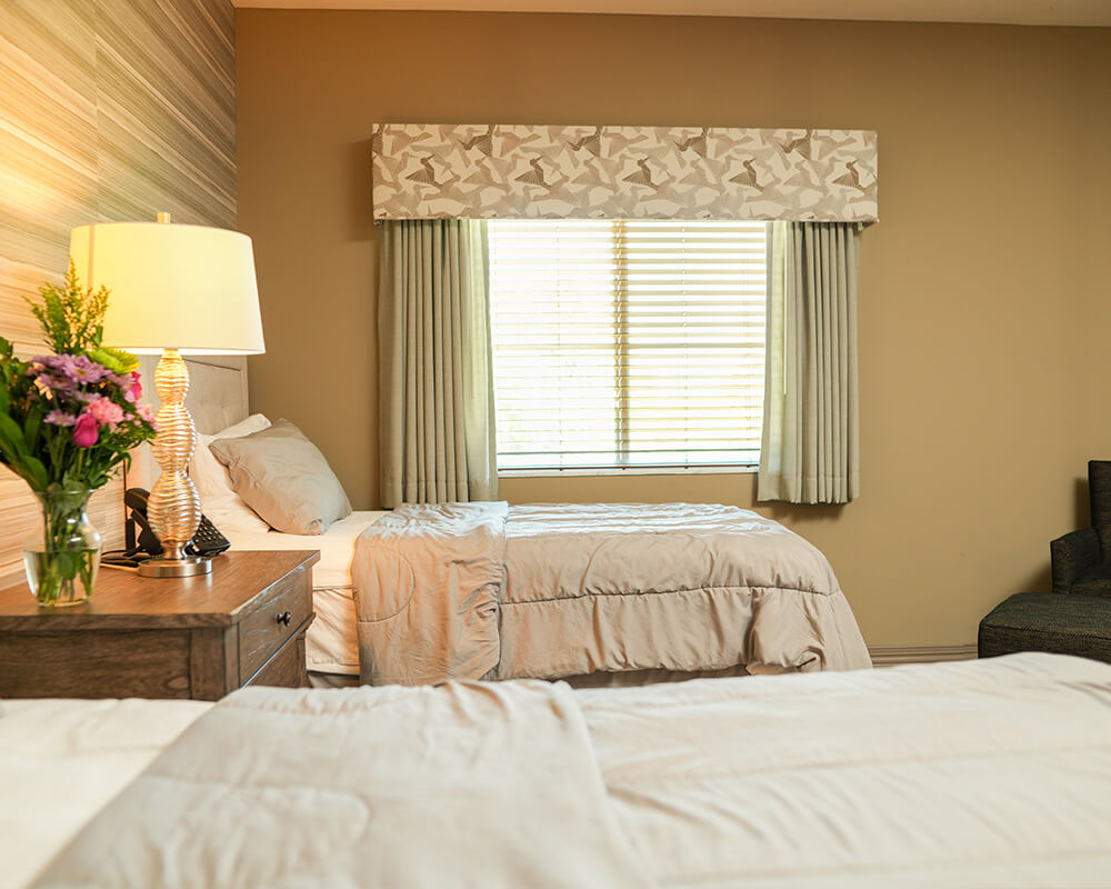 Elegant guest unit with twin beds, floral decor, and soft lighting.