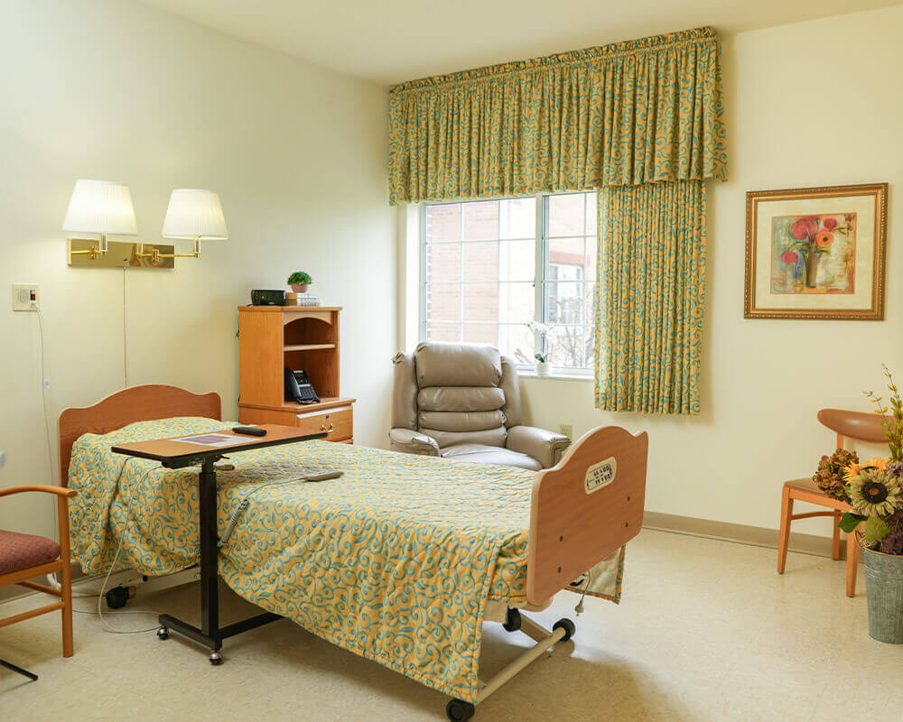Comfortable unit with medical bed, armchair, and soft lighting in senior living community.