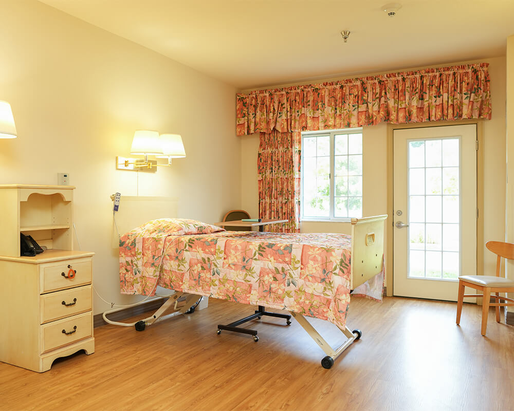 Comfortable unit with medical bed, armchair, and soft lighting in senior living community.