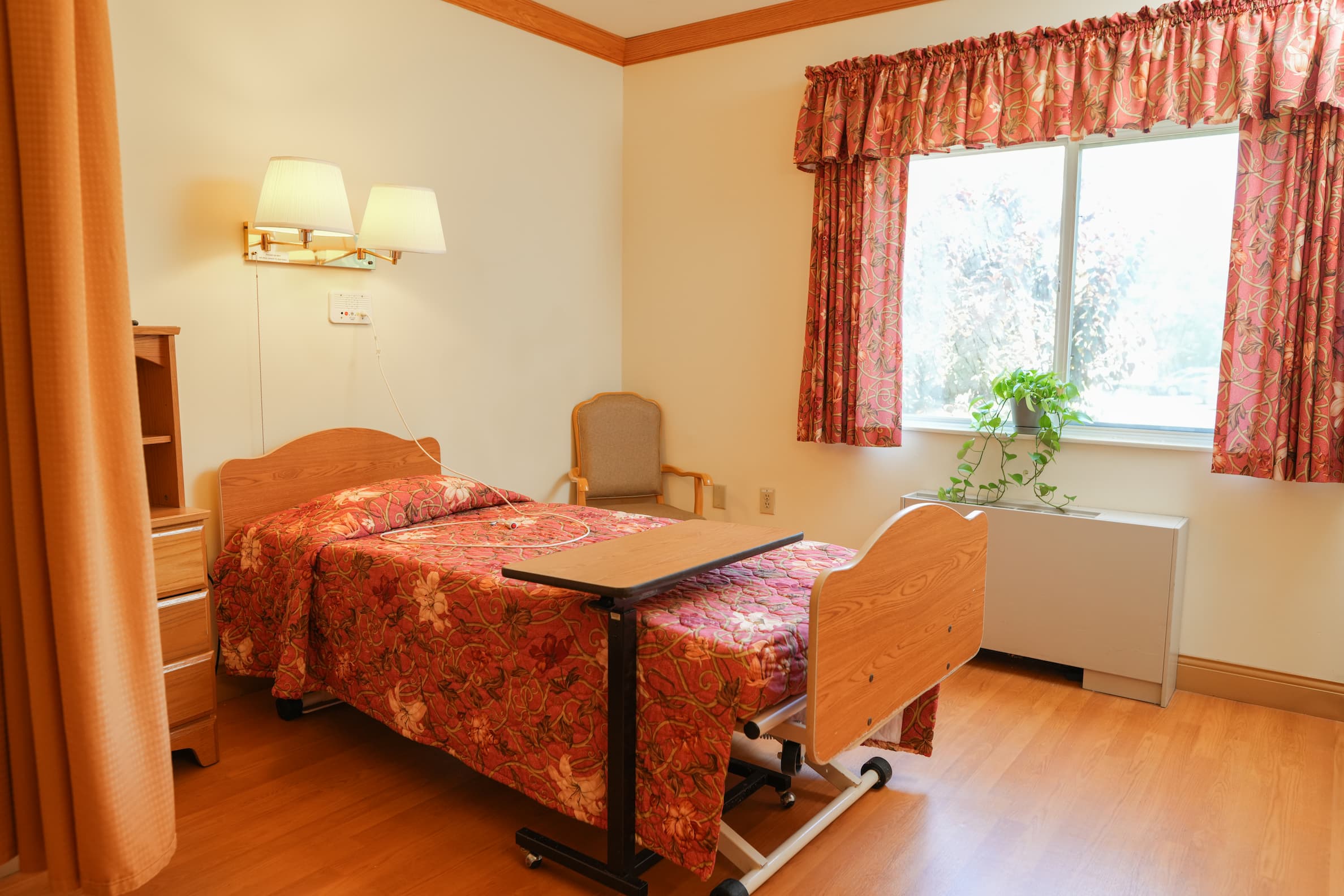 Cozy single unit bedroom with floral decor and wood furnishings.