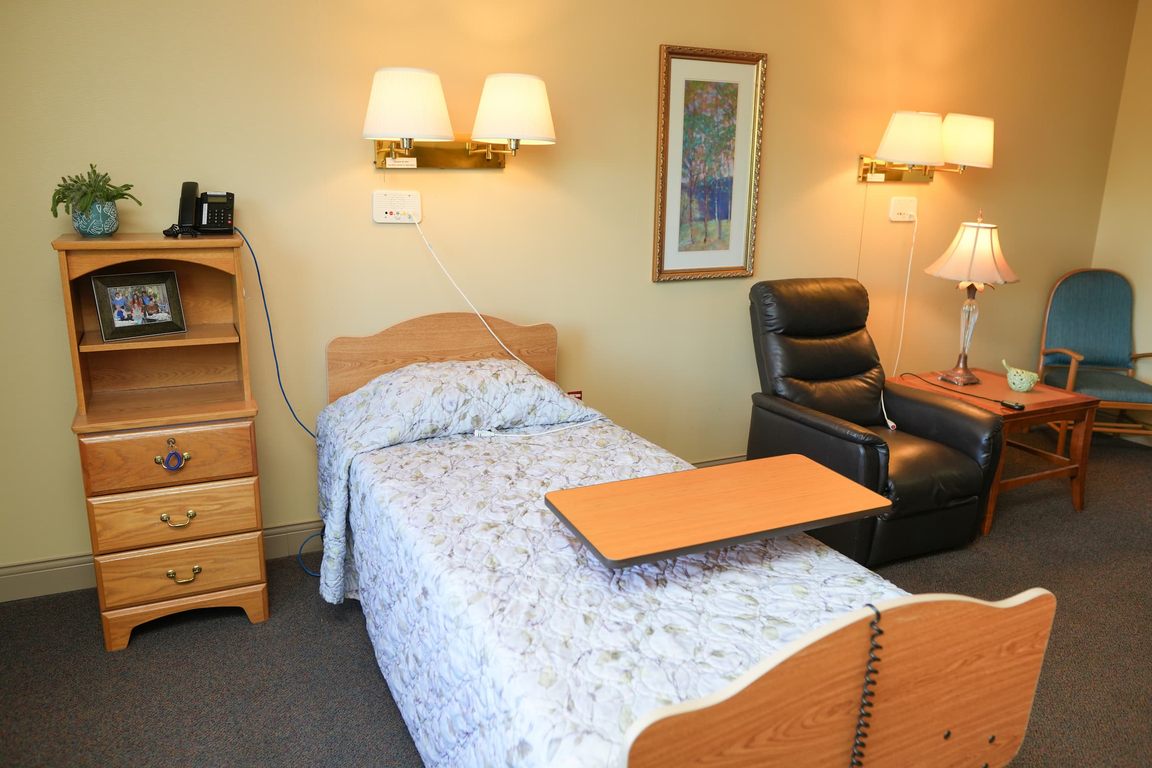 Cozy unit interior with single bed, recliner, and wooden furniture.