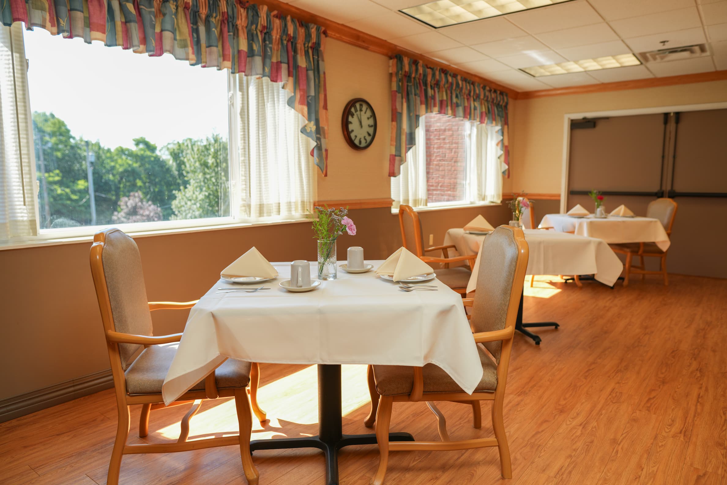 Bright dining room with set tables and chairs in a senior community.