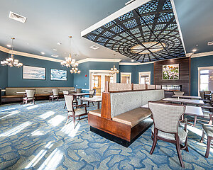 Spacious dining room in senior living unit with elegant lighting and blue decor.