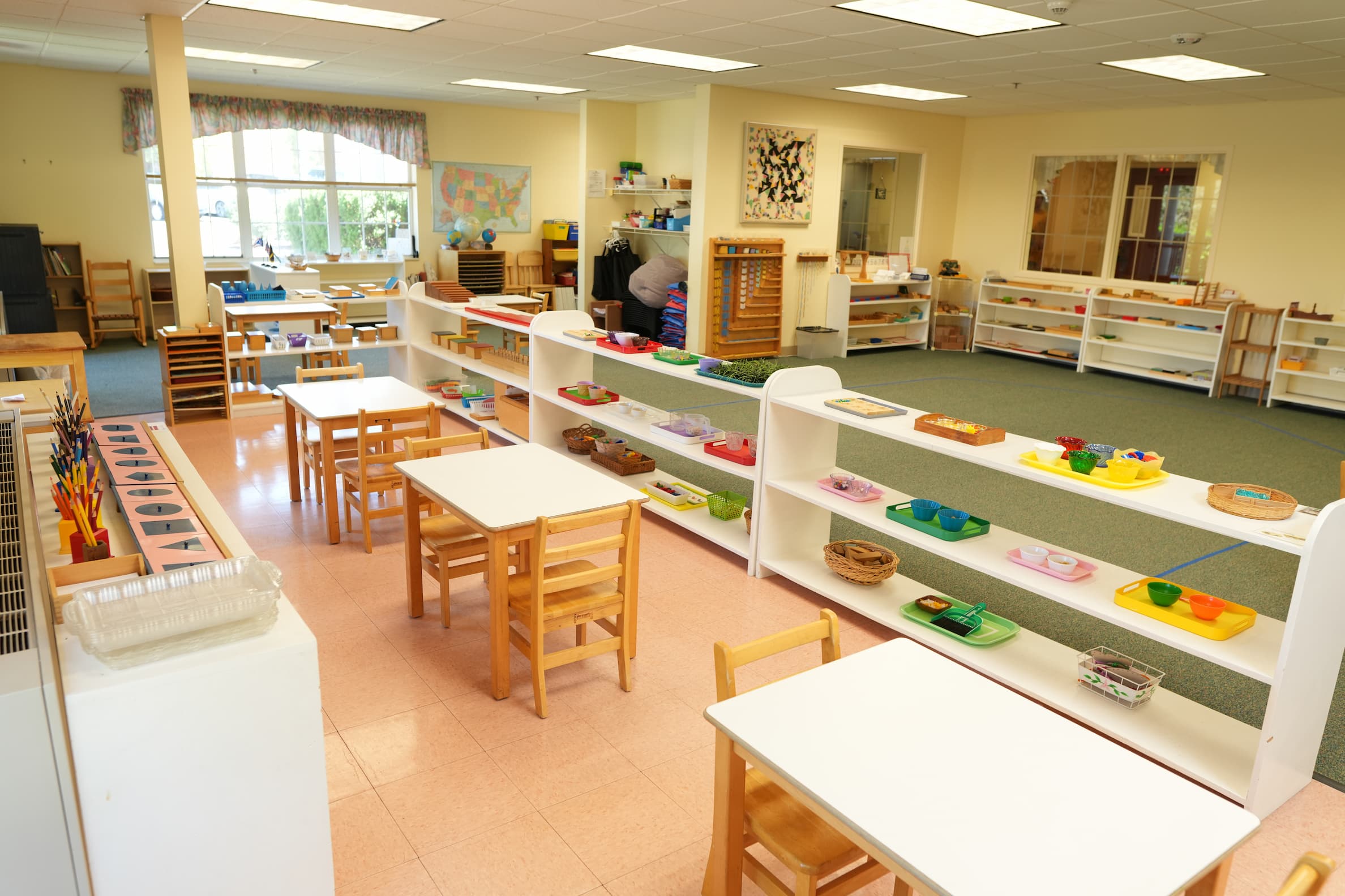 Bright classroom with small tables, chairs, and organized shelves for activities.