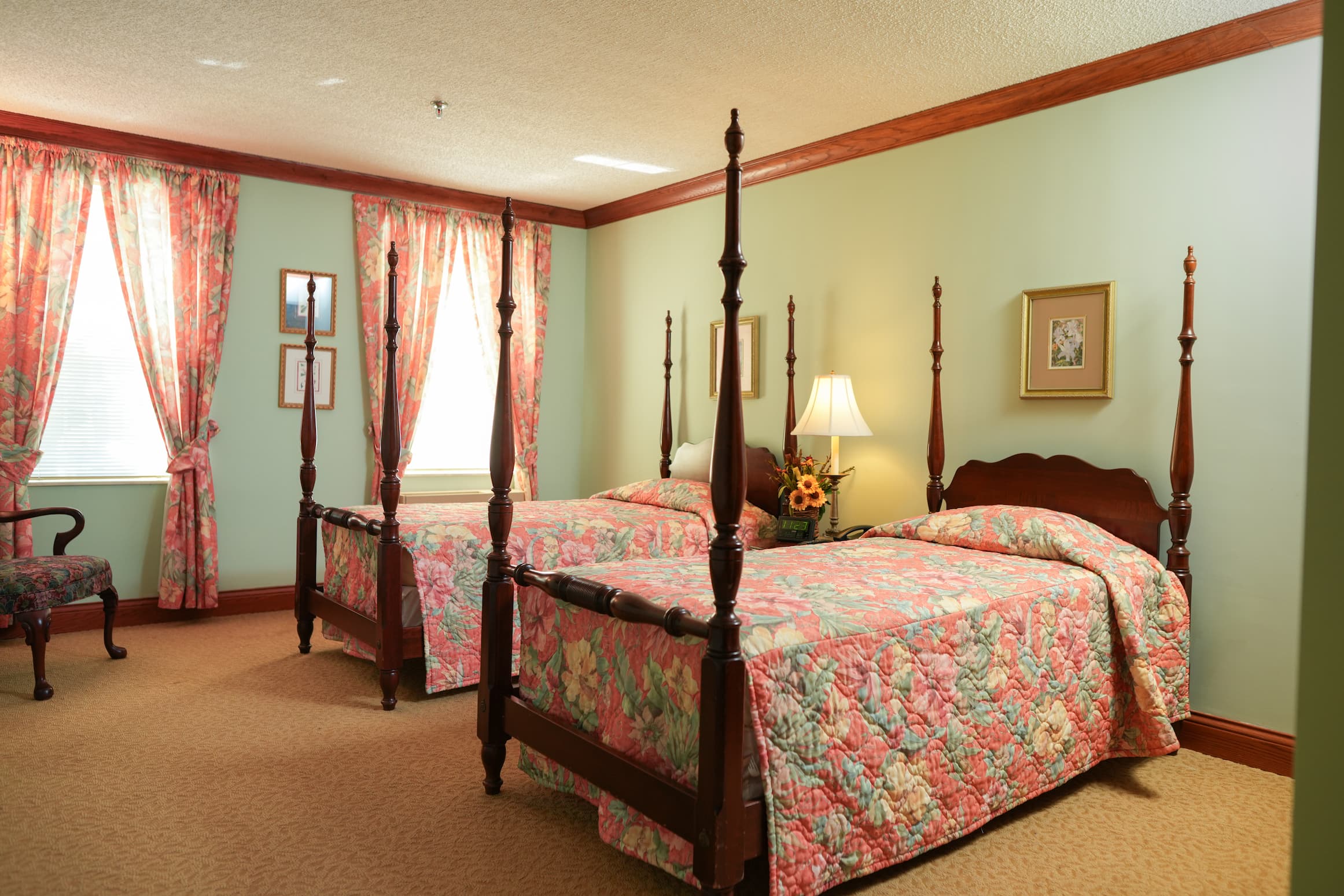 Room with two four-poster beds, floral bedding, and matching curtains.