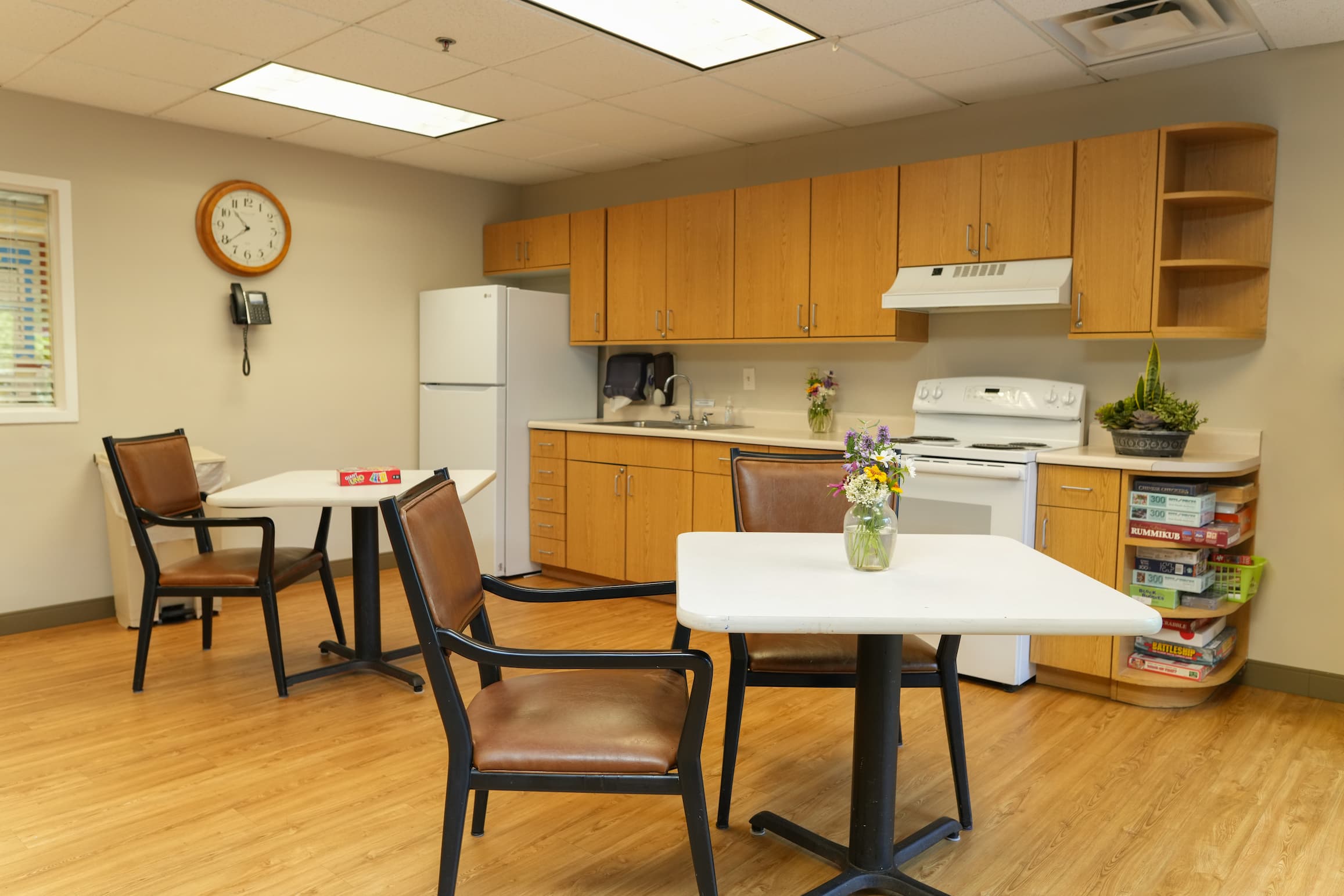 Cozy dining area with tables, chairs, and kitchen in a unit common space.