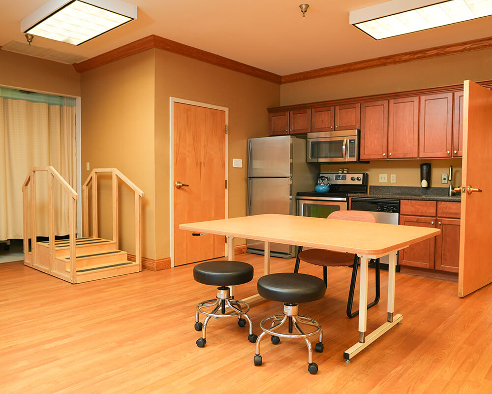 Interior of a unit with kitchen, table, stools, and wooden training stairs.