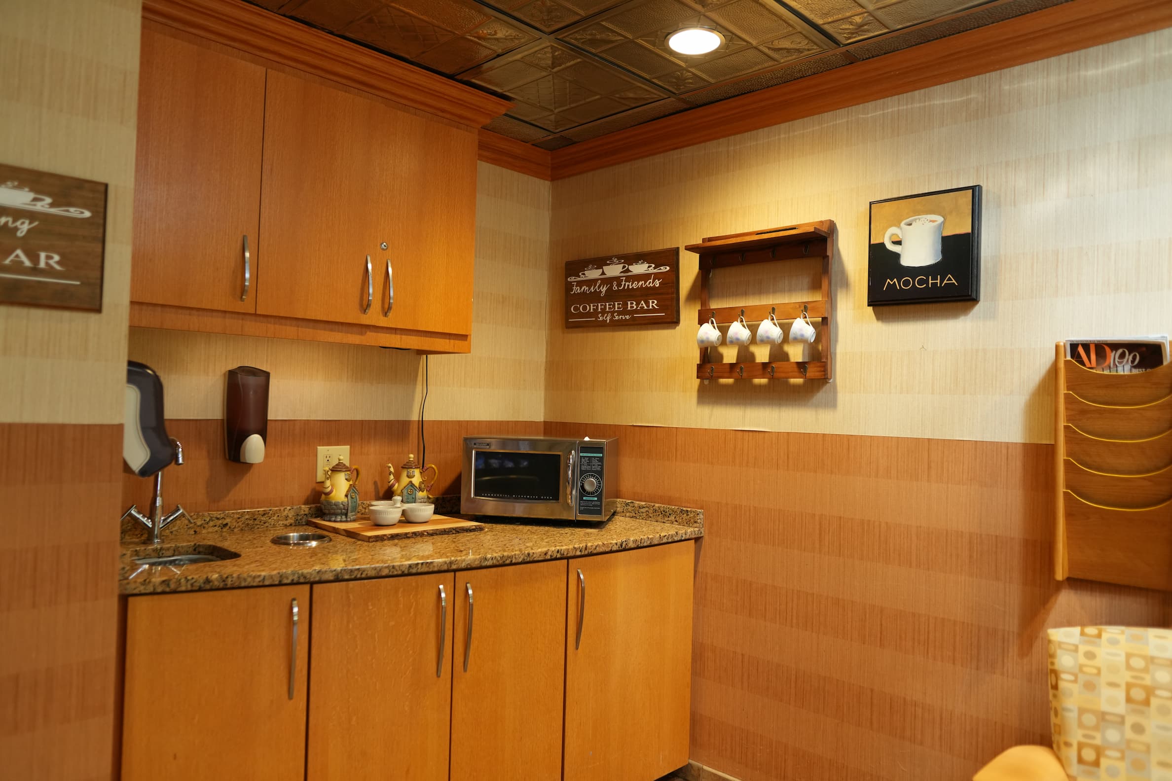 Cozy coffee corner with microwave, mugs, and wood cabinets in a living space.
